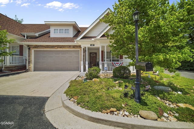 523 Apple View Way Unit 409, Sevierville, TN 37862 - view of front of house featuring a porch, driveway, an attached garage, a shingled roof, and stone siding