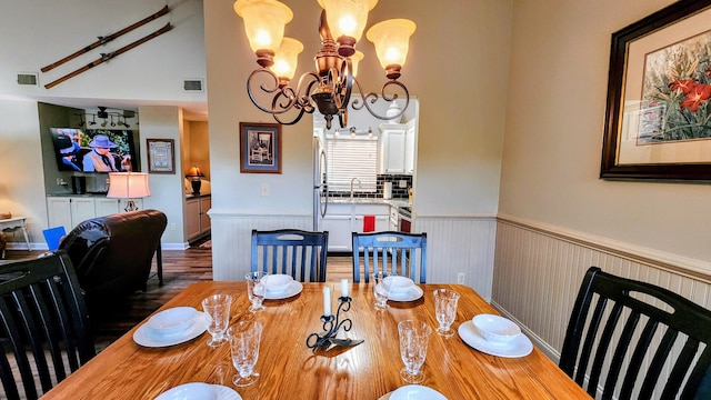 dining space with visible vents, a wainscoted wall, a chandelier, and wood finished floors