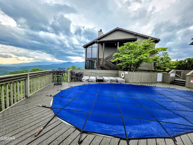 view of pool featuring a deck with mountain view, a fenced in pool, and stairs
