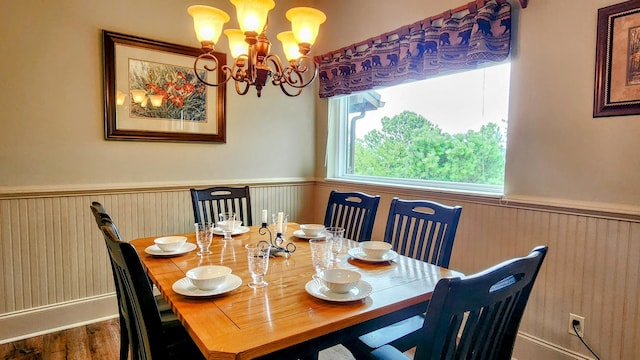 dining room featuring a notable chandelier, wood finished floors, and a wainscoted wall
