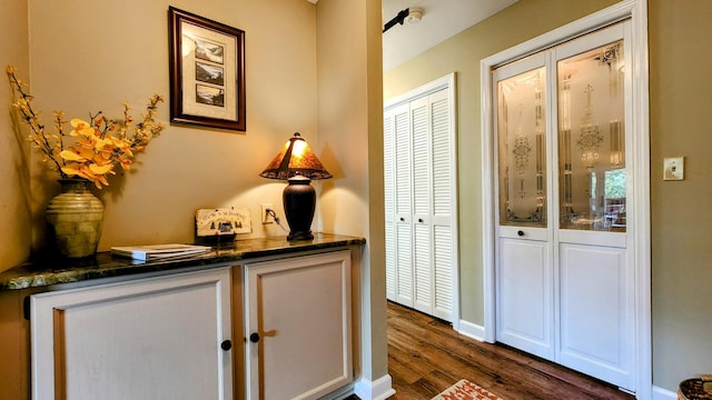 hall featuring dark wood-type flooring and baseboards
