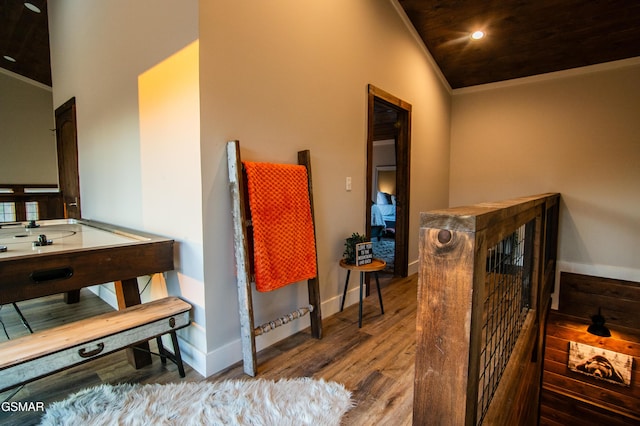 bathroom featuring vaulted ceiling, crown molding, wood finished floors, baseboards, and recessed lighting