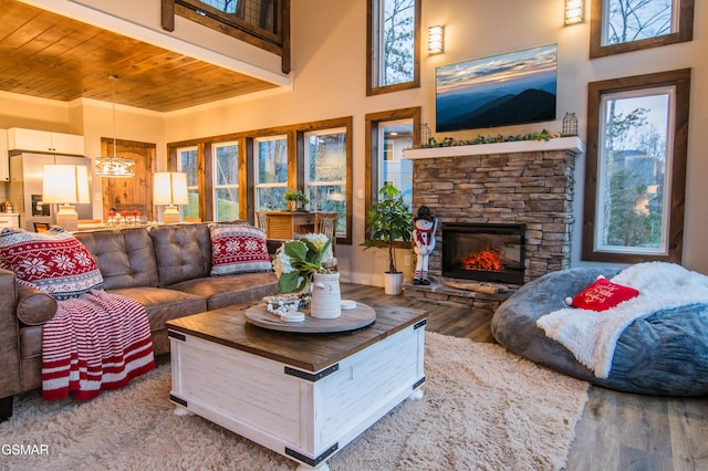 living room featuring a high ceiling, wooden ceiling, a stone fireplace, and wood finished floors