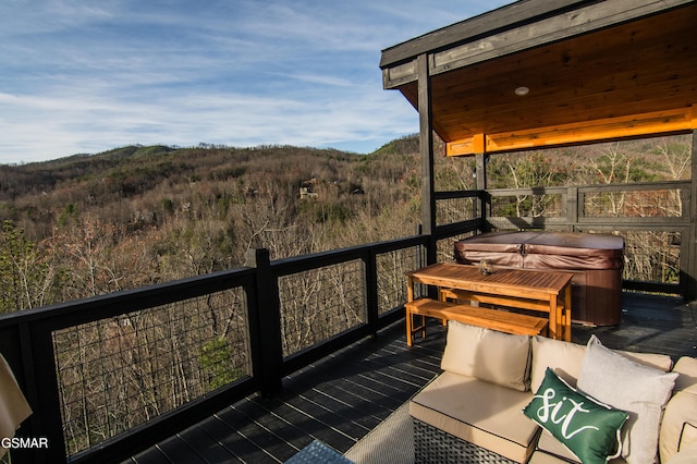 balcony with a deck with mountain view, a wooded view, and a hot tub