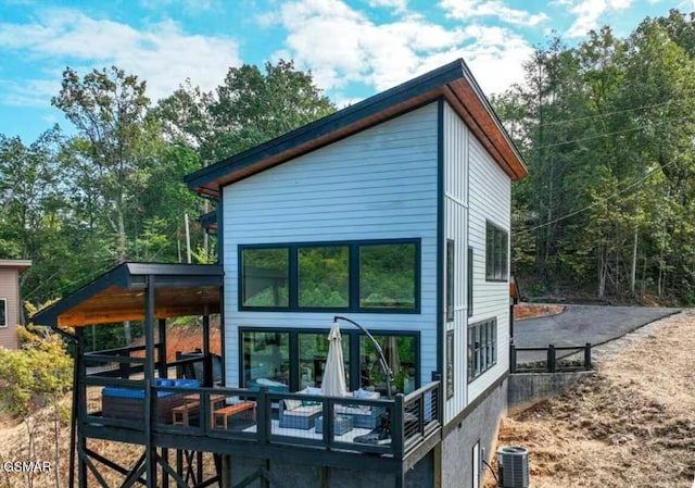rear view of house featuring driveway and central AC unit