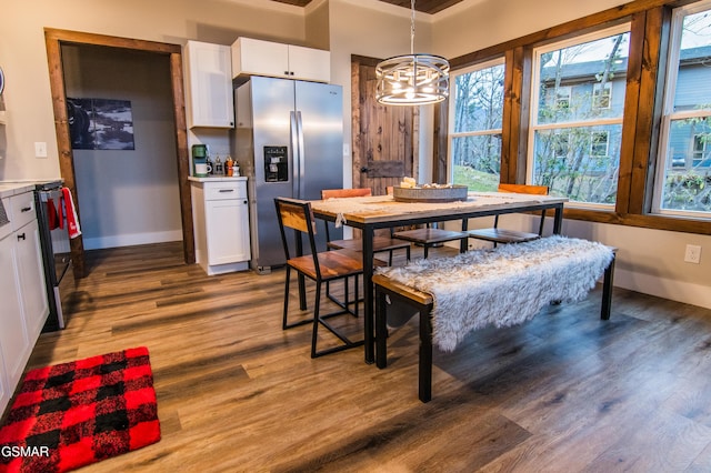 dining space featuring baseboards, wood finished floors, and a chandelier