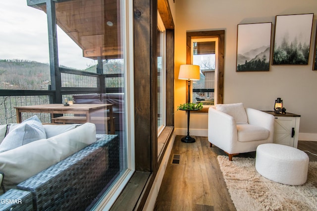 living area with baseboards, visible vents, and wood finished floors