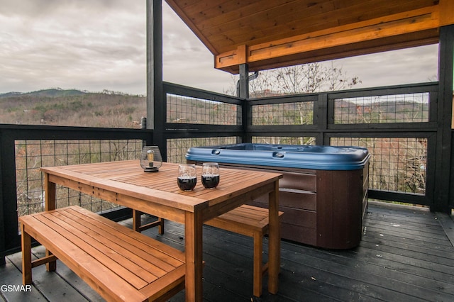 wooden terrace featuring a mountain view, outdoor dining area, and an outdoor hot tub