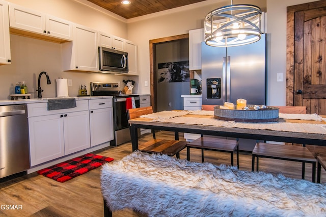 kitchen with white cabinetry, stainless steel appliances, light wood-style floors, and a notable chandelier