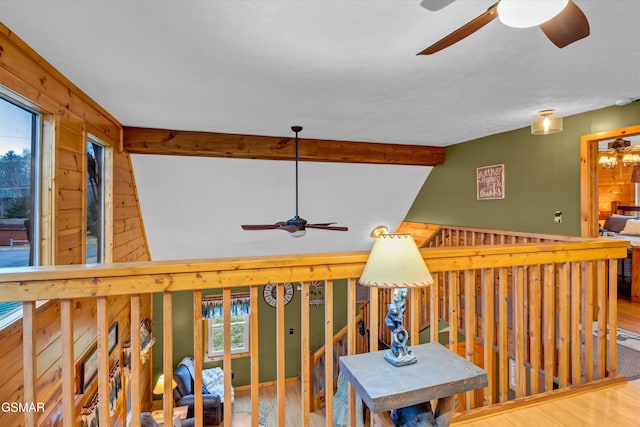 interior space with ceiling fan, wooden walls, hardwood / wood-style floors, and vaulted ceiling with beams