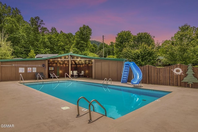 pool at dusk featuring a water slide