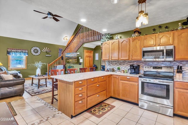 kitchen with a breakfast bar, tasteful backsplash, hanging light fixtures, appliances with stainless steel finishes, and kitchen peninsula