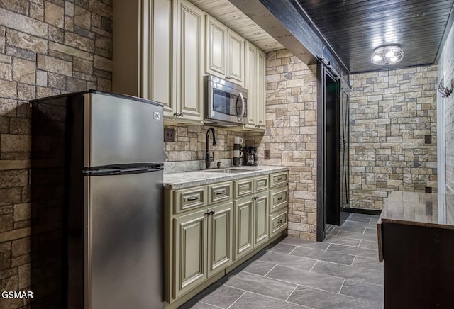 kitchen featuring appliances with stainless steel finishes, sink, wooden ceiling, and cream cabinets