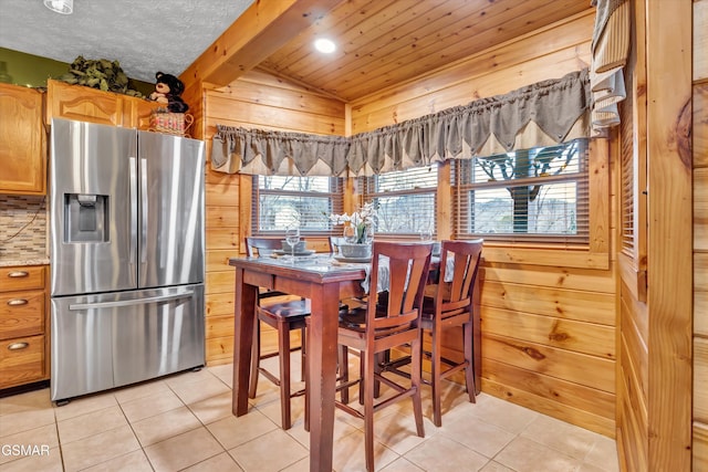 tiled dining room featuring wood ceiling, beam ceiling, wooden walls, and a textured ceiling