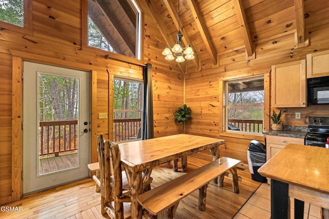 dining room with wooden walls, vaulted ceiling with beams, a notable chandelier, and a healthy amount of sunlight
