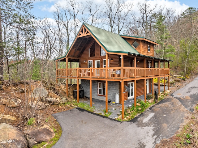 view of front facade featuring metal roof, a wooden deck, and log exterior