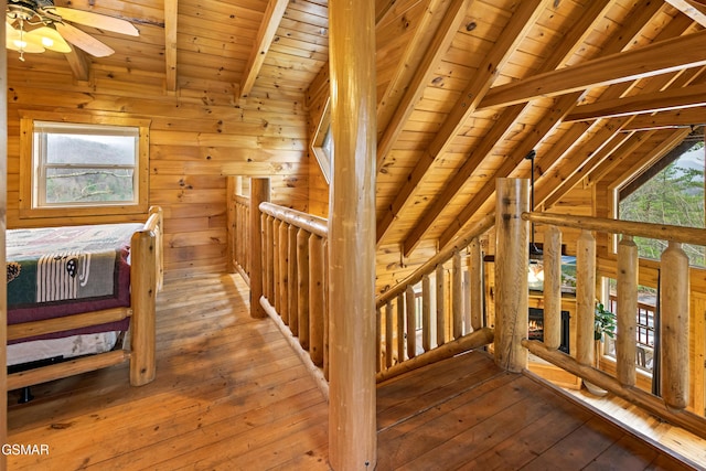 staircase with wooden walls, ceiling fan, hardwood / wood-style flooring, and lofted ceiling with beams