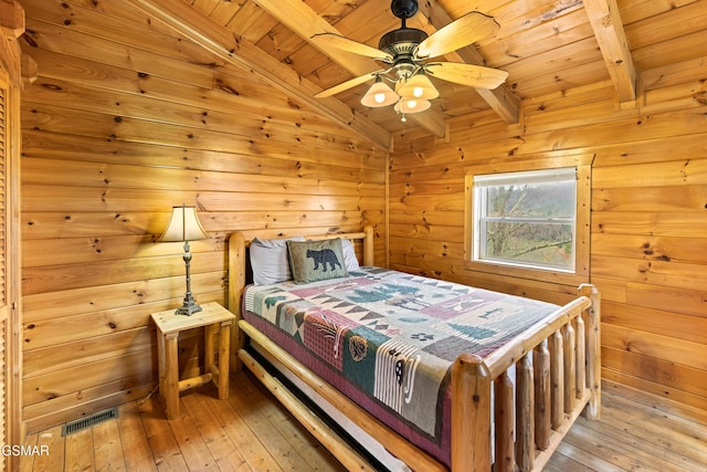bedroom with wooden walls, light wood-type flooring, lofted ceiling with beams, and wood ceiling