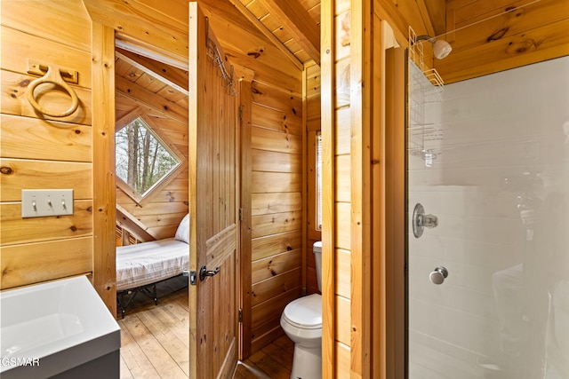 bathroom featuring a shower stall, wood-type flooring, wooden walls, and toilet