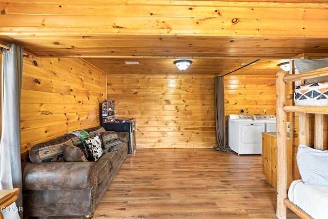 interior space with wooden walls, washer and clothes dryer, and wood finished floors
