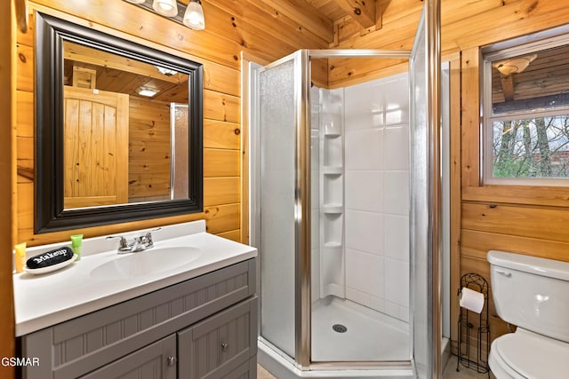 full bath with toilet, a stall shower, wood walls, and vanity