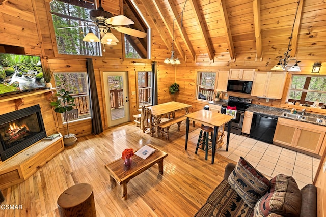 living area featuring ceiling fan, wood ceiling, wooden walls, beam ceiling, and a lit fireplace