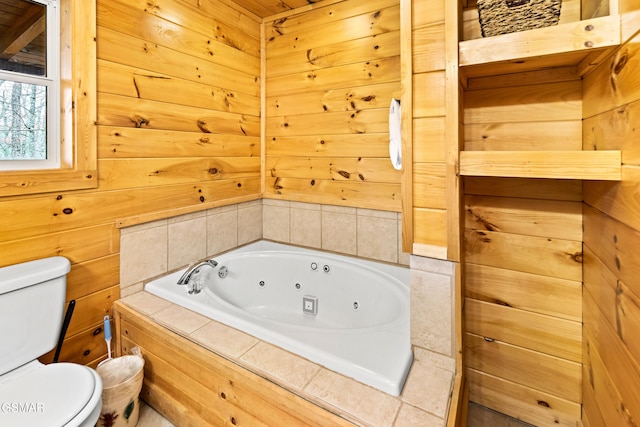 bathroom featuring a whirlpool tub, wooden walls, and toilet