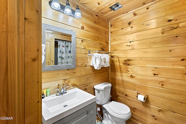 half bathroom with wood walls, vanity, and toilet