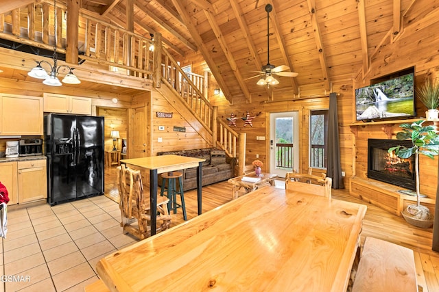 dining room featuring wood ceiling, wooden walls, beam ceiling, stairway, and a glass covered fireplace