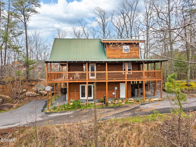 view of front of property featuring cooling unit, a wooden deck, and metal roof