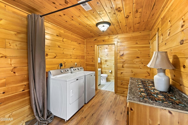 clothes washing area featuring wooden walls, light wood-style flooring, wood ceiling, and washing machine and clothes dryer