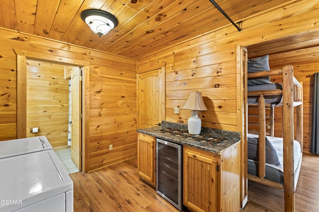 kitchen featuring dark stone countertops, washer and dryer, wood ceiling, wine cooler, and light wood-style flooring