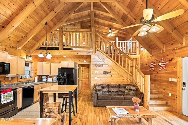 kitchen with a sink, ceiling fan, wooden walls, beam ceiling, and black appliances