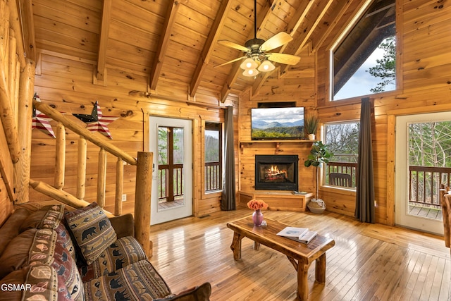 living area featuring hardwood / wood-style floors, a healthy amount of sunlight, wood walls, and beam ceiling