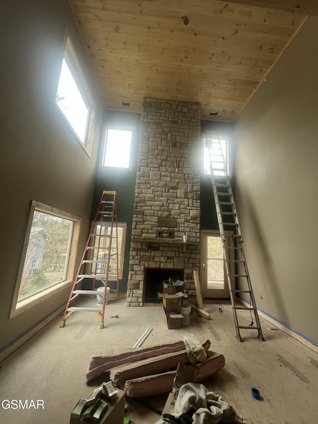 living room with a stone fireplace and wooden ceiling