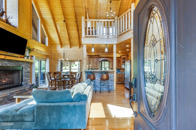 3391 Clear Valley Dr, Sevierville, TN 37862 - living area with a wooden ceiling with exposed beams, light wood-style flooring, a stone fireplace, wooden walls, and a chandelier