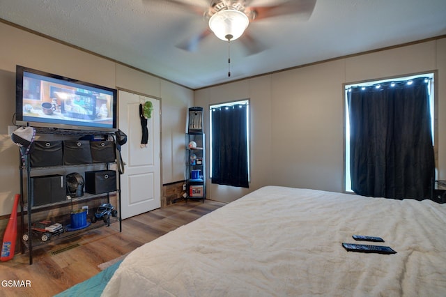 bedroom with wood finished floors, ornamental molding, and a ceiling fan