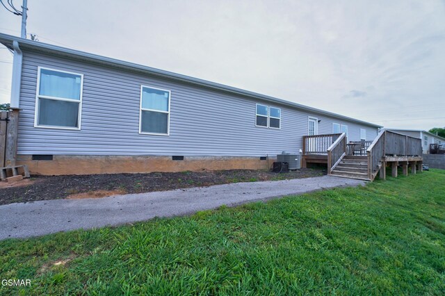back of property with crawl space, a deck, central AC unit, and a yard