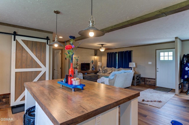 dining room featuring a textured ceiling, wood finished floors, a ceiling fan, and a barn door