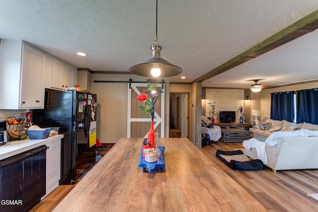 dining area with a barn door, a textured ceiling, wood finished floors, and recessed lighting