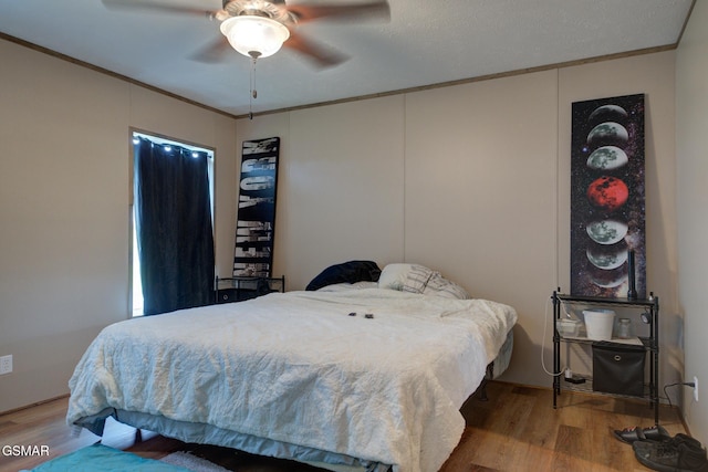bedroom with wood finished floors, ornamental molding, and a ceiling fan