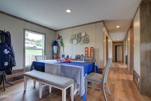 dining space with wood finished floors, a textured ceiling, and recessed lighting