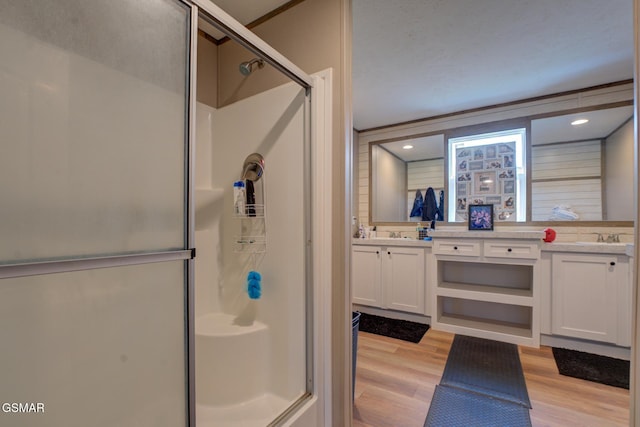 bathroom with a shower stall, wood finished floors, and double vanity