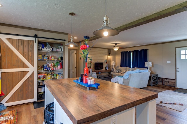 dining space featuring a textured ceiling, wood finished floors, a barn door, and ceiling fan