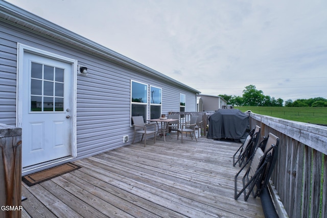 wooden terrace with outdoor dining space and grilling area