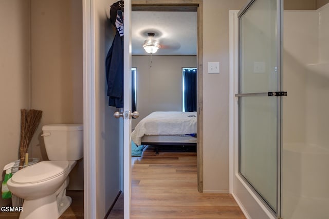 full bath featuring a shower with shower door, wood finished floors, toilet, ensuite bathroom, and baseboards