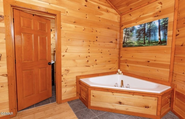 bathroom with wooden walls, a bath, and vaulted ceiling