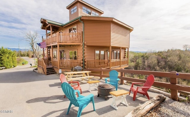 rear view of property featuring a balcony, a deck, an outdoor fire pit, and a patio