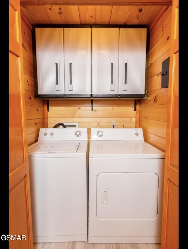 laundry area featuring washer and dryer, cabinets, wood walls, and wooden ceiling