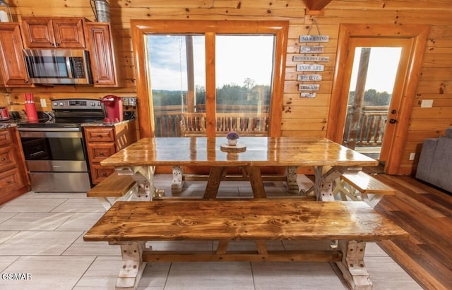 dining room featuring plenty of natural light, light tile patterned floors, and wooden walls